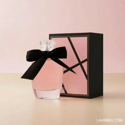 تصویر ادوپرفیوم زنانه پینک ویژوآل Pink مدل مون کور Mon Coeur حجم 100 میلی لیتر با بطری صورتی و پاپیون مشکی در کنار جعبه صورتی روی پس‌زمینه استودیویی پاستلی – عکس استودیویی اختصاصی فروشگاه لاوین